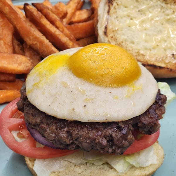 A Gili's Kitchen kosher burger with a fried egg, tomato, lettuce, and sweet potato fries.