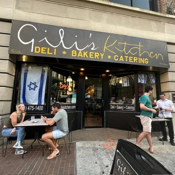 Exterior of Gili's Kitchen, a kosher deli, bakery, and catering business, with people dining outside.