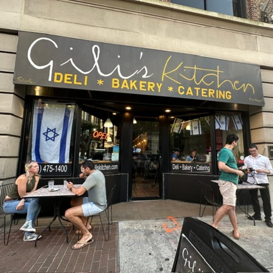 Exterior of Gili's Kitchen, a kosher deli, bakery, and catering business, with people dining outside.