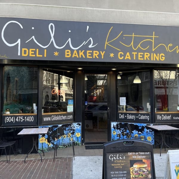 Exterior of Gili's Kitchen, a kosher deli, bakery, and catering service, with outdoor seating.