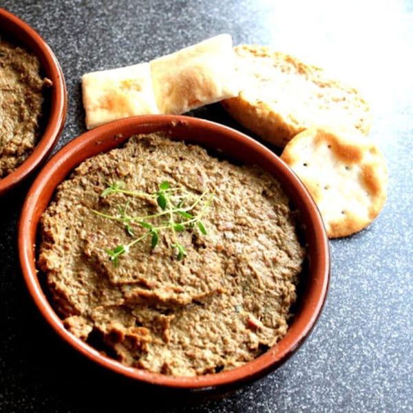 Two bowls of Gili's Kitchen kosher chopped liver, garnished with thyme, served with crackers.