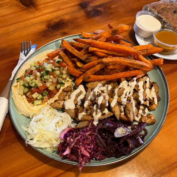 A Gili's Kitchen kosher shawarma platter with chicken, hummus, salad, sweet potato fries, and cabbage.