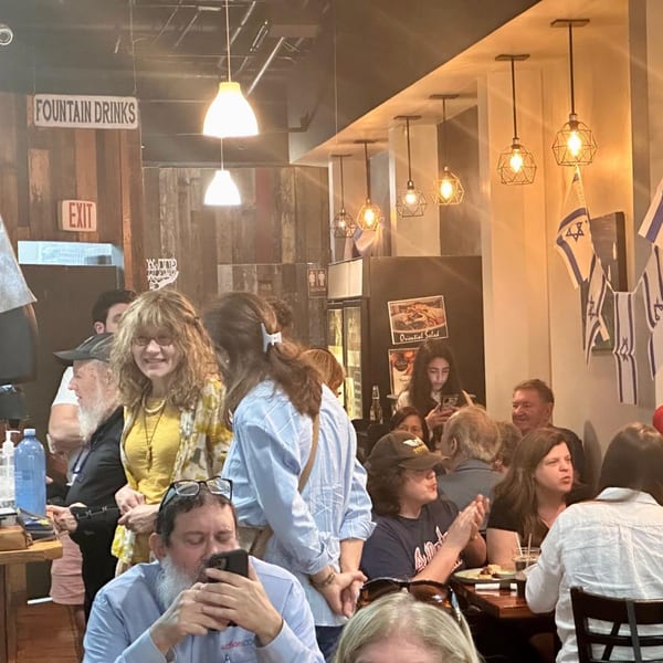 Diners enjoying the lively atmosphere at Gili's Kitchen, with Israeli flags and warm lighting.
