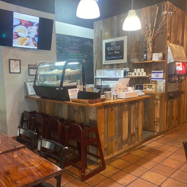 Interior of Gilis Kitchen, showing a rustic wooden counter with a display case, soda fountain, and menu board.